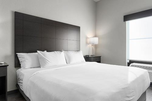 a bedroom with a large white bed with a large headboard at Riverstone Suites by Cobblestone Hotels - Chippewa Falls in Chippewa Falls