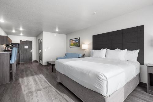 a hotel room with a large bed and a kitchen at Riverstone Suites by Cobblestone Hotels - Chippewa Falls in Chippewa Falls