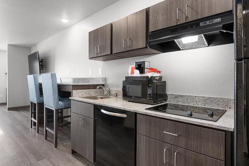 a kitchen with a sink and a microwave at Riverstone Suites by Cobblestone Hotels - Chippewa Falls in Chippewa Falls