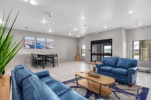 a living room with blue couches and a table at Riverstone Suites by Cobblestone Hotels - Chippewa Falls in Chippewa Falls