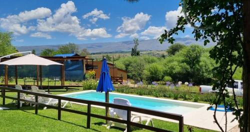 a swimming pool with an umbrella and chairs at Abrazados Suites del Valle in Villa Yacanto