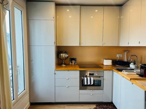 a kitchen with white cabinets and a stove at Cosy apartment-Château de Vincennes in Vincennes