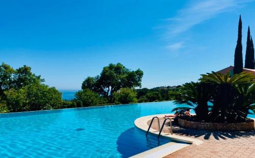 une grande piscine avec des arbres en arrière-plan dans l'établissement Mazet moderne, vue mer, clim, piscine, à Roquebrune-sur Argens