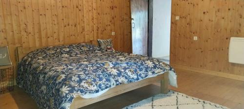 a bedroom with a bed with a blue and white blanket at L'Essentiel in Arbusigny