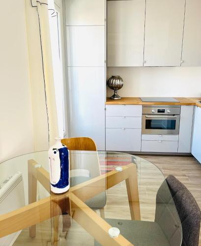a kitchen with a glass table and a kitchen with white cabinets at Cosy apartment-Château de Vincennes in Vincennes