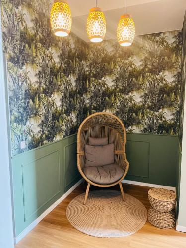 a wicker chair in a room with a floral wall at Pension Michelangelo Stadtmitte "Netflix" in Eisenach