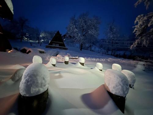 a snow covered garden at night with a christmas tree at Rubicon Cabins in Secăria