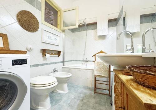 a bathroom with a toilet and a sink and a washing machine at Solemar Sicilia - Casa Pescatore in Porticello