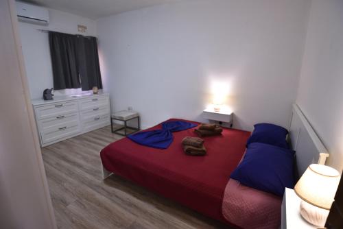 a bedroom with a bed with a red blanket and blue pillows at Sea Breeze Nest in St Paul's Bay