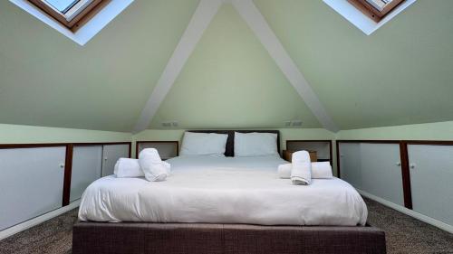 a bedroom with a large bed with white sheets and pillows at Large Modern Home Near Barking Station With SuperFast 1gbps Wi-Fi & Free Parking in Barking