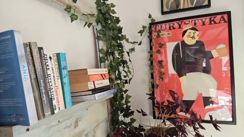a shelf with books and a poster on a wall at Miodówka in Stronie Śląskie