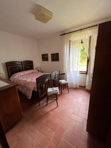 a bedroom with a bed and chairs and a window at All'Acqua Santa, immersi nella natura in Semproniano