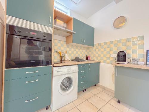 une cuisine avec des armoires bleues et une machine à laver dans l'établissement Charmant Mas centrale, bord de mer cour intérieur idéal pour 4 personnes, à Fréjus