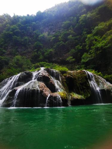a waterfall in the middle of a body of water at Zhangjiajie Twelve Warm Inn-Tianmen Mountain Ropeway Station in Zhangjiajie