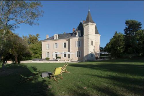 une maison avec deux chaises de jardin devant elle dans l'établissement Le Château de Monciaux, à Bourrou