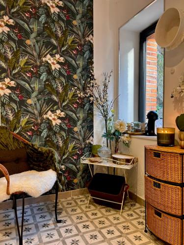 - un salon avec un mur orné d'un papier peint floral dans l'établissement La Demeure, à Sillé-le-Guillaume