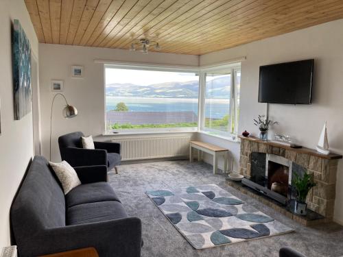 a living room with a fireplace and a large window at Eryri in Beaumaris