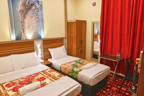 a hotel room with two beds and a red curtain at Tanha Palace Hotel in Dubai