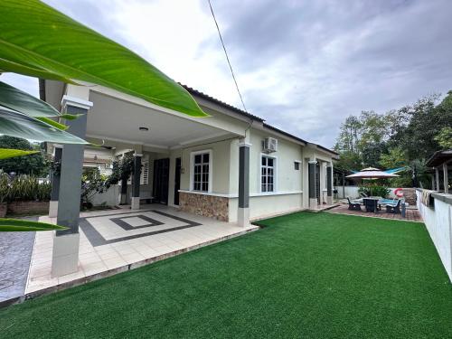 a house with a green lawn in front of it at DeCherating privatepool in Cherating