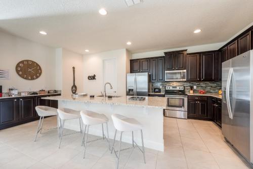 a kitchen with a large island with white stools at Grand Home Near Disney With Private Pool, Media And Themed Rooms With Waterpark & Resort Access At Encore Resorts Reunion - 360Bu in Kissimmee