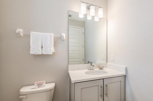 a bathroom with a sink and a toilet and a mirror at Remarkable Home Near Disney With Theater & Themed Rooms With Waterpark & Resort Access At Encore Resort - 7660Ff in Kissimmee