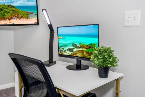 a computer monitor on a desk with a plant at Chic 1BR Parking, Rooftop, Near Arrowhd & TMobile in Kansas City