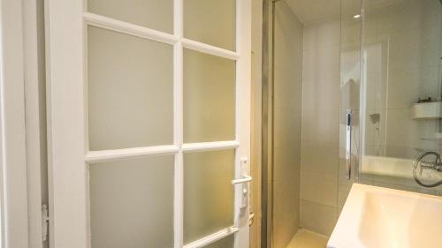 La salle de bains est pourvue d'une porte en verre menant à une douche. dans l'établissement 09 Grand Sunny flat notre dame, à Paris
