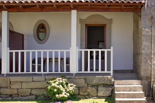 a porch of a house with a fence and flowers at Hotel Rural Casa de Samaioes in Chaves