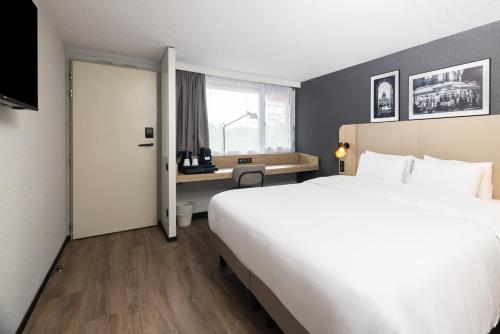 une chambre d'hôtel avec un grand lit et une fenêtre dans l'établissement Campanile NATURE - Bordeaux Est Artigues, à Artigues-près-Bordeaux