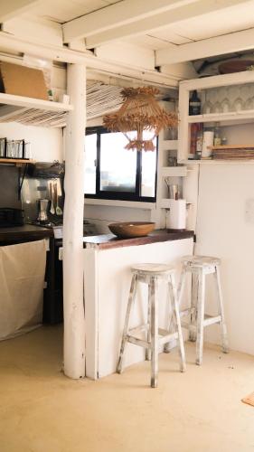 a kitchen with two stools in front of a counter at Salty House Cabo Polonio in Cabo Polonio