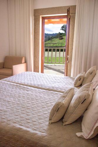 a bedroom with a bed with pillows and a window at Hotel Rural Casa de Samaioes in Chaves