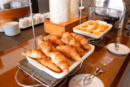 a table with several plates of croissants and bowls of bread at Hotel Rural Casa de Samaioes in Chaves