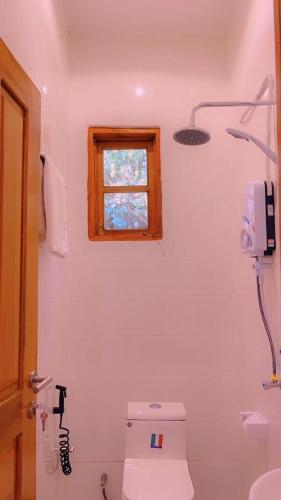 a white bathroom with a toilet and a window at Evelina House in Boma la Ngombe