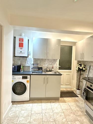 a kitchen with a washing machine and a microwave at 4 ensuite Bedroom Entire House Sleeps 10 Driveway Parking near Coventry Univesity and City Center in Coventry
