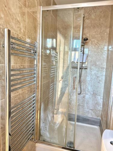 a shower with a glass door in a bathroom at 4 ensuite Bedroom Entire House Sleeps 10 Driveway Parking near Coventry Univesity and City Center in Coventry
