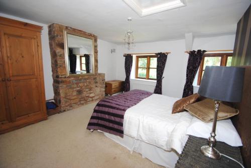 a bedroom with a large bed and a fireplace at Exmoor Farmhouse in Bampton