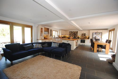 a living room with a blue couch and a kitchen at Exmoor Farmhouse in Bampton