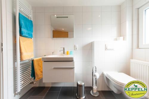 a white bathroom with a sink and a toilet at Ferienwohnungen Keppeln in Uedem