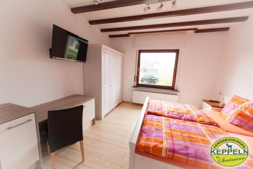 a bedroom with a bed and a desk and a television at Ferienwohnungen Keppeln in Uedem