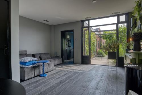 a living room with a couch and a sliding glass door at Bijzonder stadshuis met diepe moderne tuin. in Alphen aan den Rijn