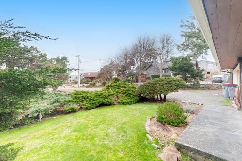 a yard with green grass and bushes next to a house at Tolovana Treasure in Cannon Beach
