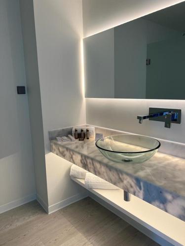 a bathroom with a glass bowl on a counter at Porto Covo Praia Hotel & SPA in Porto Covo