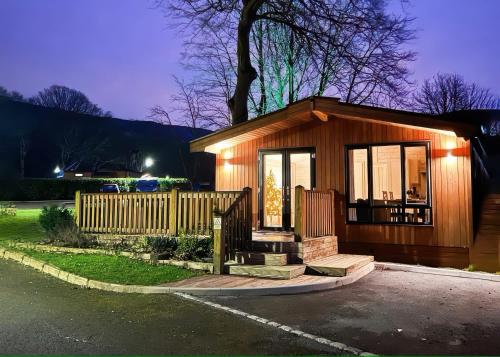 a small house with a porch and a fence at Dovestone Luxury Lodges sleeps 4- pet free in Oldham