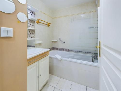 une salle de bain blanche avec une baignoire et un lavabo dans l'établissement Concarneau, appartement pour 4 personnes, à Concarneau