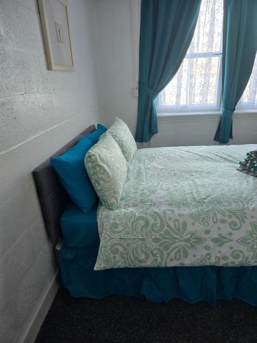 a bedroom with a bed with blue curtains and a window at The Waterfront in Greenock