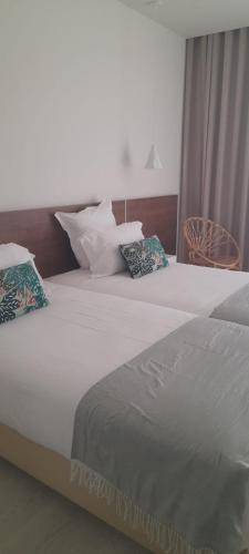 a bedroom with two beds with pillows on them at Porto Covo Praia Hotel & SPA in Porto Covo