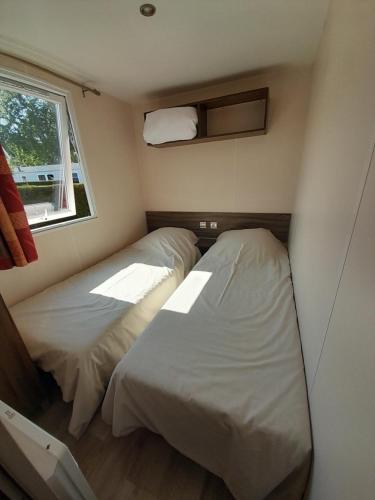 two beds in a small room with a window at Mobil home camping les Charmettes 4 étoiles les MATHES en Charente Maritime prés du ZOO de la Palmyre 8 personnes tout confort 3 chambres 2salles de bains 2 WC Lave linge lave vaisselle Climatisation bien situé in Les Mathes