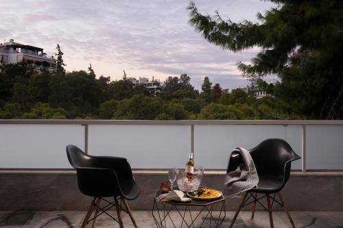 two chairs and a table with a plate of food on a balcony at Athenian Riviera Hotel& Suites in Athens