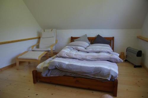 a bedroom with a bed and a chair in it at Schwalbenhaus-Netzow in Templin