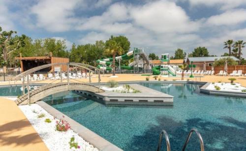 un parc aquatique avec un pont et un toboggan aquatique dans l'établissement Mobil-home Comfort XL 3 chambres 6 pers, au Grau-du-Roi